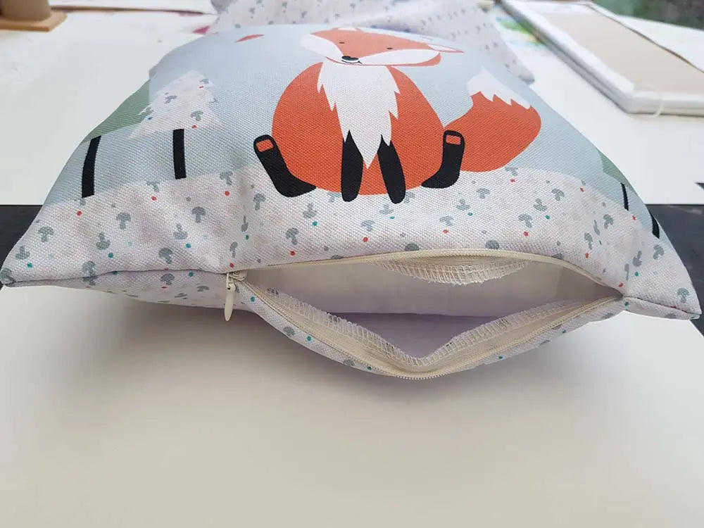 Coussin chambre bébé avec renard roux assis et champignons décoratifs.